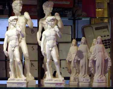 Statuette kitsch del ''David'' di Michelangelo e della madonna, fianco a fianco in una vetrina. Foto G. Dall'Orto